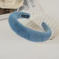 Close-up of blue plush headband with Hand Made label next to a white metal basket - Blue