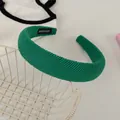 Detail of green wide headband with knit texture and handmade tag on a metal basket - Oil Green