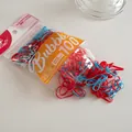 Detail of red and blue elastic hair ties spilling from a 100-piece pack for daily styling - Red and Blue