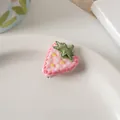 Close-up of a pink strawberry fabric hair clip with embroidery on a ceramic plate - Pink Strawberry