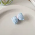 Dettaglio del fermaglio per capelli a fiocco vichy blu su un piatto di ceramica - Fiocco Blu