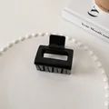 Primer plano de una pinza para el pelo geométrica negra brillante en un plato de perlas - Estilo Cuadrado Pequeño