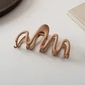 Detailed view of large matte light brown claw clip with elegant wave design - Khaki