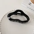 Detailed view of a glossy black hollow wavy hair claw clip on a white ceramic tray - Cloud Style (8#)