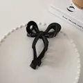 Detail of glossy black bow hair claw clip displayed on a minimalist white ceramic plate - Bowknot Style (9#)