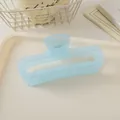 Détail d'une pince à cheveux rectangulaire bleu clair mat de 13cm sur un plateau chic - Bleu clair gelée