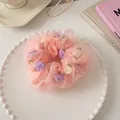 Detalle de coletero de organza rosa con rosas de tela moradas y crema en plato blanco - Rosa