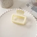 Detailed view of a square cream-colored hair claw clip on a decorative white tray - Bright White