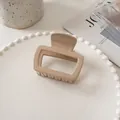 Macro shot of minimalist beige square hair claw clip on a decorative pearl tray - Milk Coffee