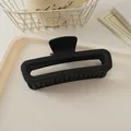 Gros plan d'une pince à cheveux rectangulaire noire mate de 13 cm sur plateau élégant - Noir mat