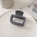 Detail of dark grey square hair claw clip with embossed lettering inside on a white plate - Gray