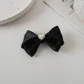 Detail einer schwarzen Satin-Schleifen-Haarspange mit funkelndem Herz-Strass-Besatz - Schwarz
