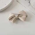 Nahaufnahme einer champagnerfarbenen Satin-Schleifen-Haarklammer mit Herz-Strass-Detail - Champagner-Grau