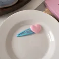 Primer plano de una pinza para el pelo con corazón azul en un plato blanco para niña dulce - Clip Azul con Corazón Rosa
