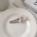 Detail van roze emaille metalen strik haarclip met zilveren randen op keramiek - Lichtroze boog