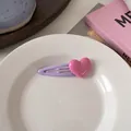 Macro di una dolce clip per capelli a forma di cuore macaron su un piatto di ceramica - Clip Viola con Cuore Rosa Lampone