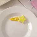 Detail of yellow triple-layer star-shaped hair clip on a white decorative plate - Yellow