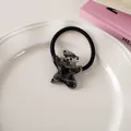 Macro view of cartoon bear hair tie with marble texture and black heart detail on ceramic tray - Inky Color - Hair Tie