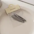 Detailansicht von zwei Haarspangen aus gebürstetem Metall auf einem Keramikteller - Schlanke Massiv/Hohl Oval Kombination (6#)