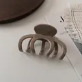 Close-up of a large glossy khaki hair claw clip with multi-tooth design on a marble table - Grey Coffee