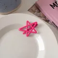 Close-up of a pink hollow star-shaped hair clip on a white ceramic plate for summer styling - Rose Pink Star