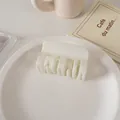 Detalle de una pinza para el cabello cuadrada de color crema sobre un plato blanco - Blanco Brillante