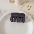 Close-up of a glossy deep purple hair claw clip on a white decorative ceramic tray - Deep purple