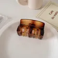 Primer plano de una pinza de pelo rectangular ámbar de carey en un plato blanco - Ámbar