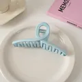 Makro-Detail einer großen hellblauen Wellen-Haarklammer auf weißem Keramikteller - Überkreuz-Stil / Hellblau