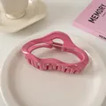 Detailaufnahme einer rosa gewellten Haarklammer auf einem Keramikteller im Wohnambiente - Wolken-Stil / Himbeerrosa
