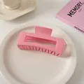 Detail einer großen glänzenden rosa rechteckigen Haarklammer auf weißem Keramikteller - Quadratischer Stil / Hellrosa