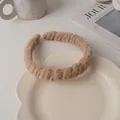 Detail view of cream plush twisted headband with soft texture on a decorative plate - Light Coffee