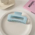 Detail einer hellblauen glänzenden Haarklammer auf einem weißen Keramikteller - Quadratischer Stil / Hellblau