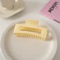 Detailansicht der cremegelben Haarspange aus glänzendem Harz auf einem Keramikteller - Quadratischer Stil / Milchiges Gelb