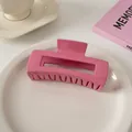 Glänzende rose-pinkfarbene rechteckige Haarklammer auf einem Keramikteller serviert - Quadratischer Stil / Himbeerrosa