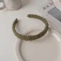 Detail of moss green sherpa fleece headband on a white ceramic plate with cozy decor - Grass Green