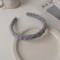 Detailed texture of dark grey lamb wool headband on a white ceramic plate - Gray