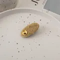 Detail einer khakifarbenen Teddy-Fleece-Haarspange mit goldener Metallschnalle im Keramiktablett - Ingwergelb