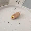 Detail einer beigen Teddy-Plüsch-Haarspange mit goldenem Knopf auf einer Keramikschale - Koreanisches Rosa