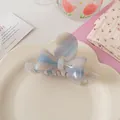 Détail macro d'une pince à cheveux nœud en acétate avec marbrure rose bleue et lettres dorées - 9.5cm / Blanc Marbré Dégradé