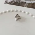 Polished silver hollow heart metal hair claw clip displayed on a white ceramic plate - Hollow Heart - Silver