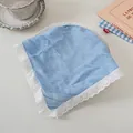 Detail eines hellblauen Baumwolltuches mit weißer Spitze auf einem gedeckten Tisch - Blauer Streifen