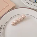 Dettaglio dei fermagli per capelli a cuore rosa perlato su un piatto di ceramica bianca - Rosa Perlato - Cuore Puro