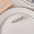 Dettaglio di cinque perle bianche a forma di cuore su un fermaglio in metallo argentato - Bianco Perlato - Cuore Puro