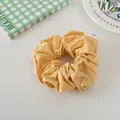 Detail of a ginger yellow pleated cotton scrunchie with brand label on a cozy background - Yellow