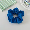 Detail of a dark blue scrunchie with a white fabric label on a decorative background - Klein Blue