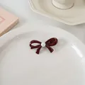 Vue détaillée d'une pince à cheveux vintage rouge avec un nœud et une perle élégante - Noeud de Perles
