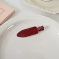 Detail einer Vintage dunkelroten Haarklammer auf einem weißen Keramikteller in sanfter Umgebung - Nahtlose Clip