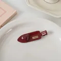 Détail de la pince à cheveux cœur bordeaux avec gravure dorée LOVEDAYS sur plateau - Pince cœur sans trace