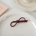 Détails d'une pince à cheveux rouge foncé en forme de nœud sur une assiette en céramique - Nœud en forme de 8